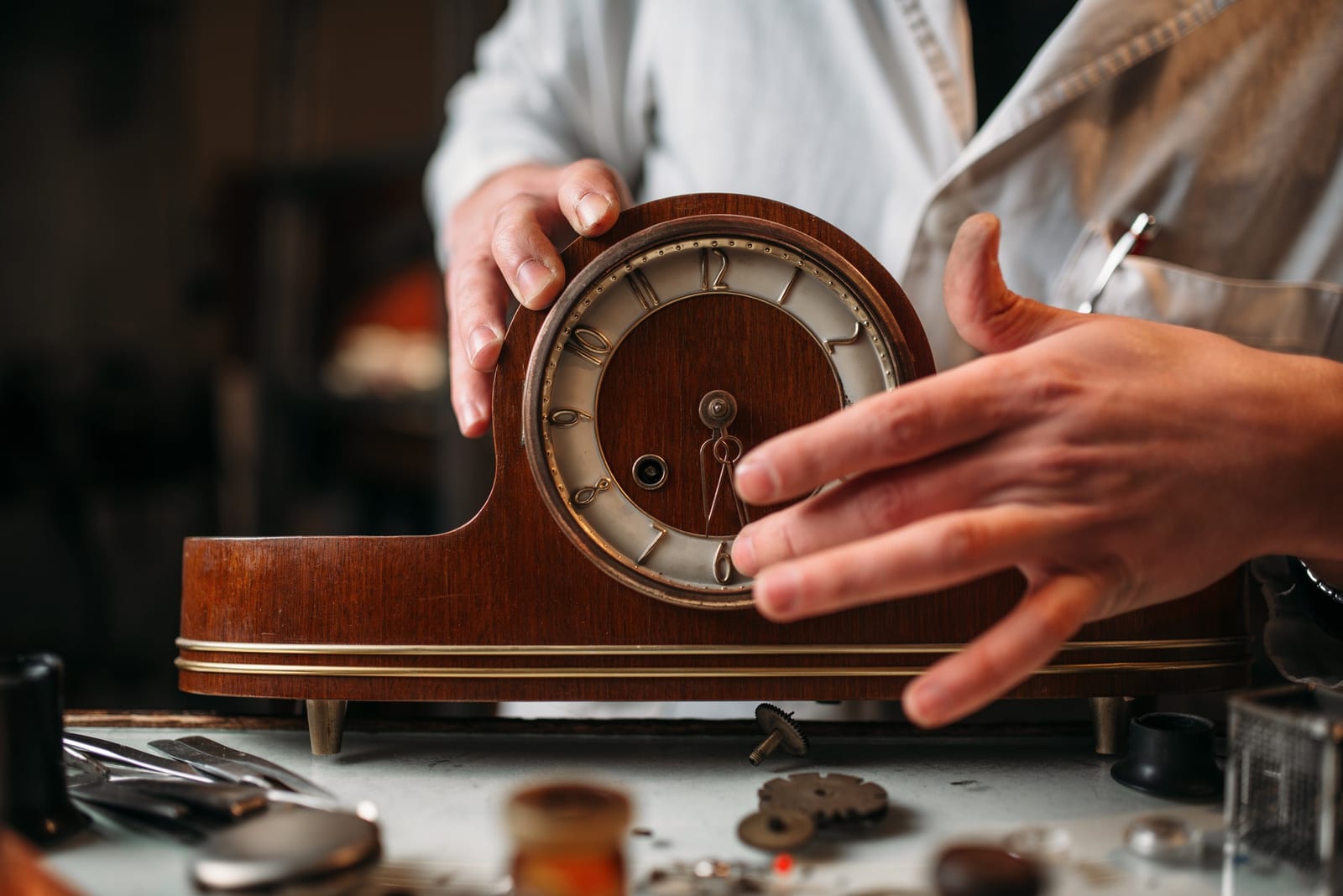 Orologiaio che restaura un vecchio orologio da tavolo in legno